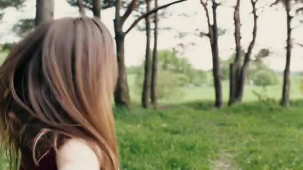 Femme tourne son visage, sourit à la caméra alors qu'elle court dans la nature. Les cheveux foncés se balancent. slow mo, steadicam shot — Video