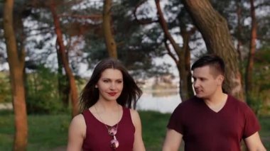 Güzel esmer çift doğada yürüyüş gülümseme, birlikte iyi eğlenceler. Mutlu ve memnun görünüyorlar. Yavaş mo, steadicam vurdu
