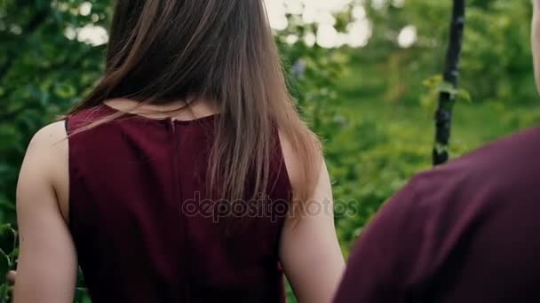 La mano delle donne tocca le foglie. Bella giovane donna cammina davanti al suo uomo, gira la testa Backview slow mo, colpo steadicam — Video Stock