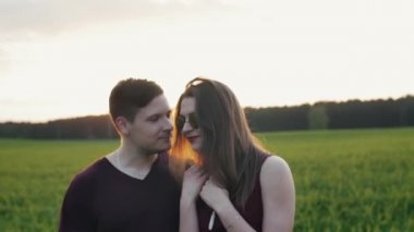 Doğa gülümseyen severler. Gün batımı, konuşmak ve gülmek alanına yürüyorlar. Kadın güneş gözlüğü takıyor. Yavaş mo, steadicam vurdu