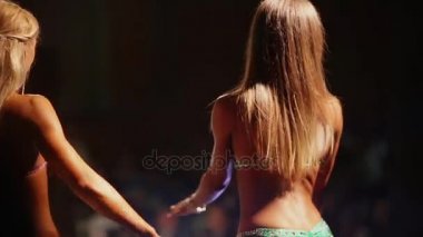 İnce seksi kız fitness yarışmaları bikinili poz. Perde arkasından görünümü.