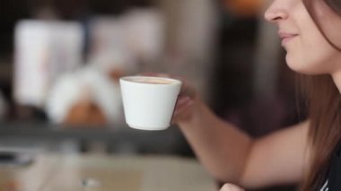Güzel kadın bir fincan kahve sahiptir. Güzel bir kızın sahip bir fincan kapuçino veya latte, yan yan.