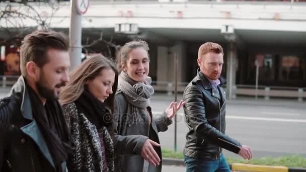 Widok boczny uśmiechający się ludzie wesoło chodzą w pobliżu drogi w centrum miasta. Spacer z przyjaciółmi i czat. Steadicam strzał, zwolnionym PN — Wideo stockowe