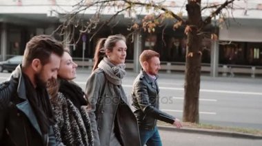 Gülümseyen insanlar neşeyle şehir merkezinde road yakınındaki yan görünüm. Arkadaşlar yürüyüş ve sohbet. Atış, Steadicam yavaş mo