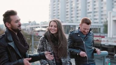 İki yakışıklı delikanlı ve güzel bir kız konuşmak ve şehir köprüsü üzerinde duran gülümse. Atış, Steadicam yavaş mo