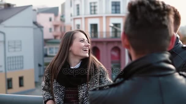 Young beautiful girl talks to two men, emotionally laughs. Red-haired man gesticulates. Slow mo, steadicam shot — Stock Video