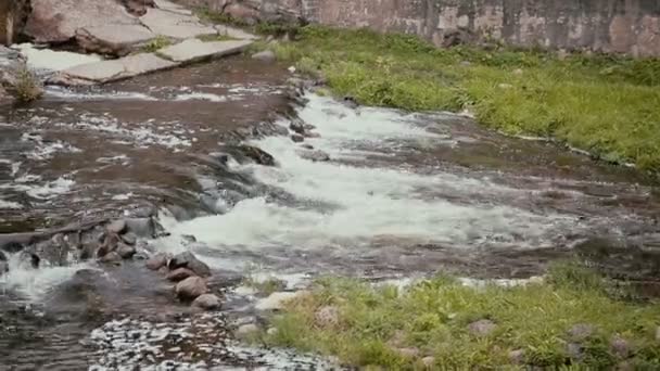 Un primer plano de una corriente de agua que baja de una pequeña cascada con ruido fuerte — Vídeo de stock