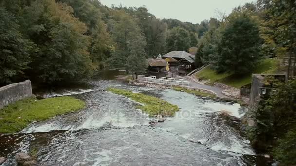Una vista dalla cima su un bellissimo fiume di montagna che scende in un grazioso edificio in legno creando cascate mozzafiato — Video Stock