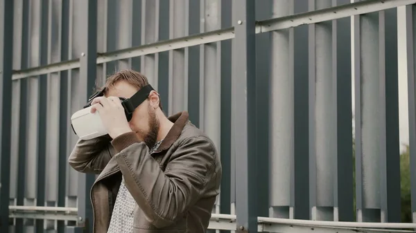 Γενειοφόρος άνδρας ελκυστική χρησιμοποιεί γυαλιά εικονικής πραγματικότητας στο αστικό χώρο. 4k — Φωτογραφία Αρχείου