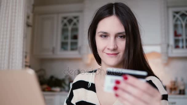 Jovem atraente sorrindo mulher usa plástico cartão de crédito compras on-line com laptop . — Vídeo de Stock