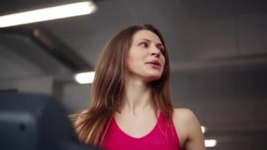 Spor salonunda egzersiz. Atletik kadın bir koşu bandı üzerinde çalışıyor. Önde ve yana arıyorsunuz.