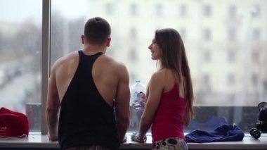 Sportif delikanlı ve konuşurken bir spor kulübü penceresinde yakın duran kadın. Kadındır içme suyu egzersiz yaptıktan sonra