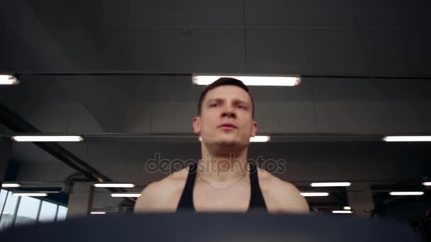 Sporty man is concentrated on his workout. Athletic man is running on a treadmill. Working out in a sport club. — Stock Video