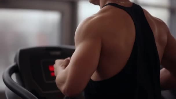 Rug en zijde bekijken van een sterke bodybuilder draaien op een loopband tijdens het trainen in een sportclub. Gezonde levensstijl. — Stockvideo