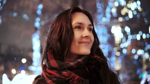 公園の木の前でカメラを見て雪のクリスマス夜笑顔で魅力的な女性装飾輝くライト — ストック写真