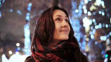 parlak ışıklar, kamera önünde park ağaçlar bakarak karlı Noel gecesi smiles çekici kadın dekore