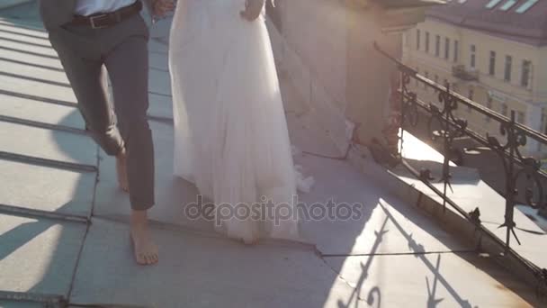 Ευτυχισμένο ζευγάρι κομψή νύφη και ο γαμπρός περπατήματος στη στέγη. — Αρχείο Βίντεο