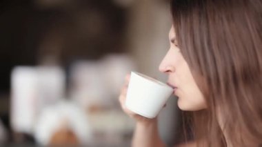 Genç esmer kadın kahve içme yan görünüm. Kadının bir fincan kahve var. Yakın çekim