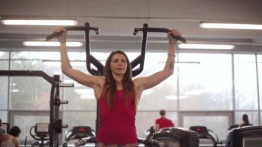 Bir spor kulübü çalışma dışarı. Genç sportif kadın spor ekipman pull-up yapıyor.