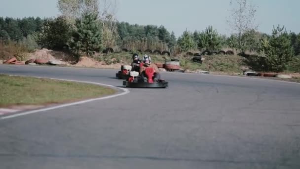 Dois motoristas em uma pista de kart movem-se para a câmera e passam por ela. Corrida de kart Go . — Vídeo de Stock