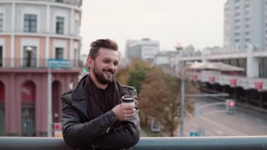 Neşeyle gülümseyerek, paket servisi olan restoran kahve veya çay tutan bir sakal ve trendy saç kesimi olan bir şık yakışıklı adam. Yavaş mo
