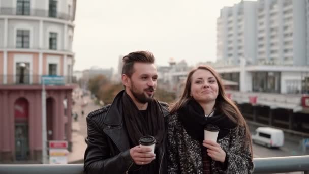 Jonge knappe man en een mooie jonge brunette meisje lachen emotioneel, afhaalmaaltijden kop koffie. — Stockvideo