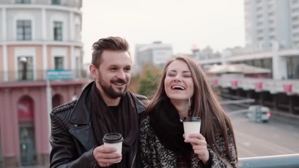 Young handsome man and a beautiful young brunette girl laughing emotionally, having takeaway coffee. Slow mo — Stock Video