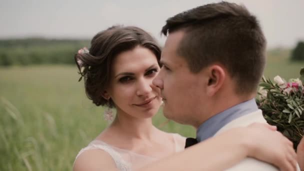 Close-up of a beautiful bride. She hugs her groom and tenderly looks in camera then into his eyes. Wedding day — Stock Video