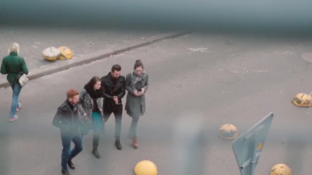 Blick hinunter auf die Straße, wo vier junge, stylische Leute spazieren gehen. Zwei Mädchen und zwei Männer gehen spazieren. slow mo, steadicam shot — Stockvideo