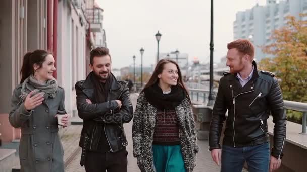 Due belle ragazze e due uomini alla moda camminano in città, parlano emotivamente, sorridono. Lento mo, colpo steadicam — Video Stock