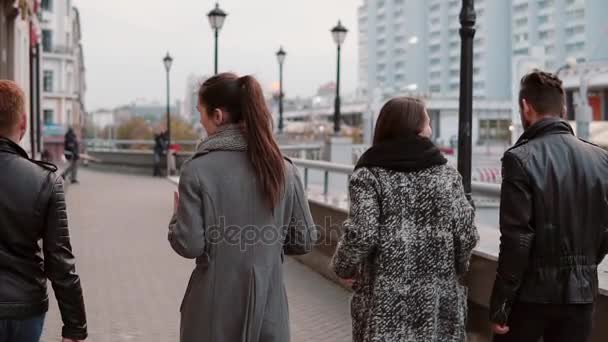 Deux filles branchées et deux hommes élégants marchent joyeusement dans la ville et parlent. Mois lent, prise de vue steadicam, vue arrière — Video