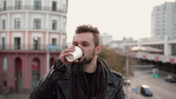 Um homem bonito elegante com uma barba bebendo café takeaway ou chá olhando para o lado . — Vídeo de Stock