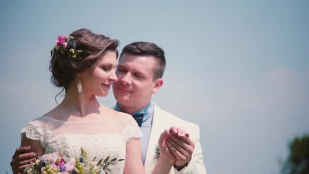 Feliz novio sosteniendo suavemente su bonita mano de novias y mirándola. Pareja de pie en el campo, accesorios de boda — Vídeos de Stock