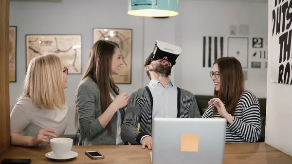 Hombre guapo intenta aplicación para gafas de realidad virtual casco VR sus amigos y colegas que lo apoyan en la oficina moderna — Foto de Stock