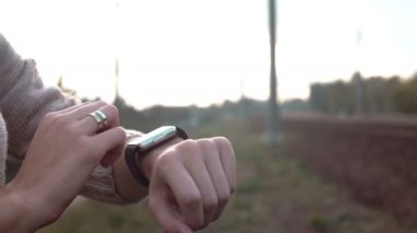 Onun smartwatch dokunmatik ekran cihaz bir kırsal arka plan üzerinde 4 k kullanan kadın
