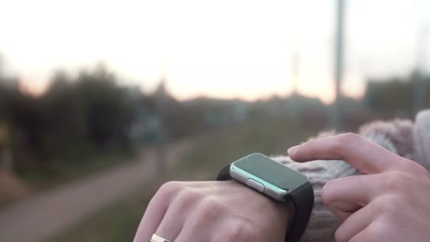 Mulher usando seu dispositivo de tela sensível ao toque smartwatch em um fundo rural 4k — Vídeo de Stock