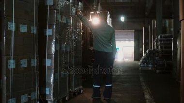 Üniformalı erkeklere bir depoda çalışıyor. Yükleyici paletleri ile bu üzerindeki yükü taşımaları. Paketleri raflar