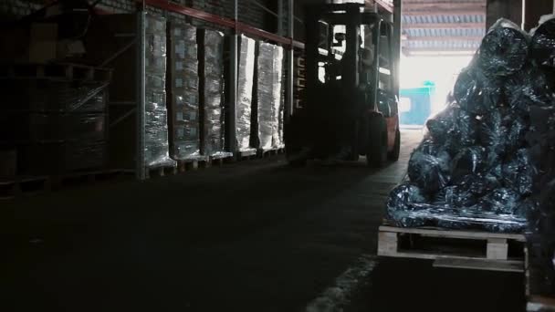 En gaffeltruck kran lyfter en palett med kartonger i ett lagerställe för lagring med ljud. Rutorna på hyllor. — Stockvideo