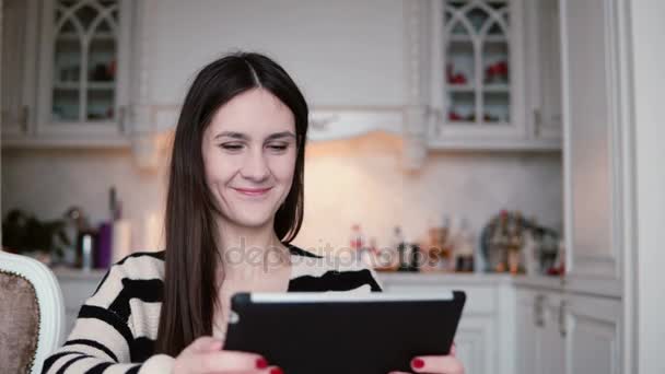 Retrato de una hermosa joven morena usando tableta pantalla táctil en un comedor luminoso . — Vídeo de stock