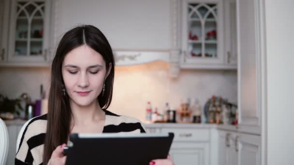 Bella giovane coppia uomo e donna utilizzando telefono e tablet touchscreen in una sala da pranzo luminosa . — Video Stock