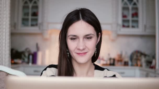 Porträt einer schönen jungen brünetten Frau mit Laptop in einem hellen Esszimmer. — Stockvideo