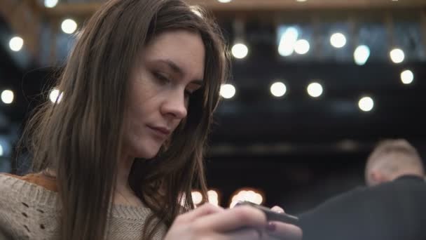 Retrato de perto. Mulher usando seu dispositivo touchscreen smartphon em modernas luzes de café no fundo 4k — Vídeo de Stock