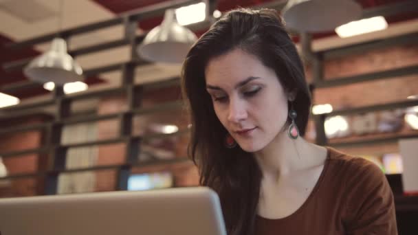 Молодая брюнетка работает на ноутбуке в кафе . — стоковое видео