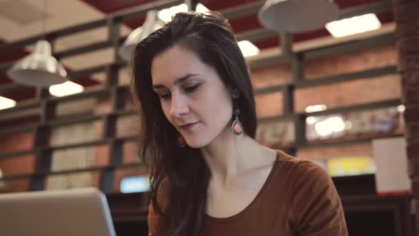 Fiatal barna lány dolgozik a laptop a kávézóban. — Stock videók