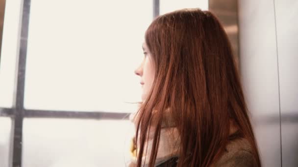 Joven mujer atractiva en ascensor de cristal bajando. Chica morena mirando a la ventana y pensando. 4K — Vídeos de Stock