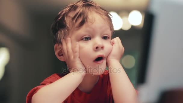 Cansado bonito menino em camisa vermelha segura as mãos perto do rosto, tocando bochechas e ter um rosto engraçado olhando . — Vídeo de Stock