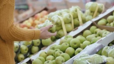 Bir elma bir elma tutan süpermarkette seçme kadın s el yakından görmek. Meyve ile vitrin. 4k
