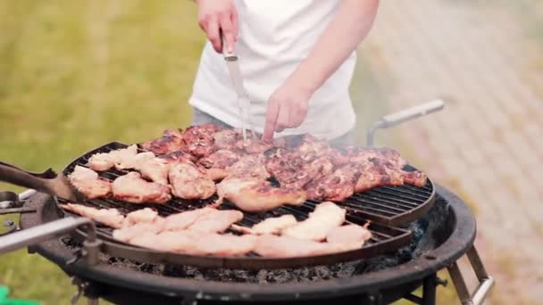 Mans cooking chicken on barbecue grill outdoor in the summer. The smoke coming from the meat. — Stock Video