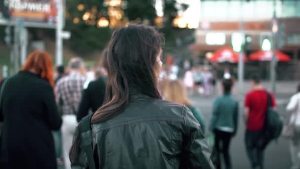 Attractive young woman crossing street in the city at a crosswalk. Slow motion, steadicam shot, back view. — Stock Video