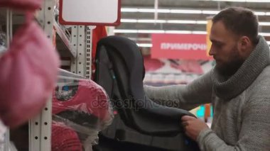 Genç adam deposunda raflarda öğesini seçerek güle güle Bebek Oto Koltuğu için istiyor. 4k